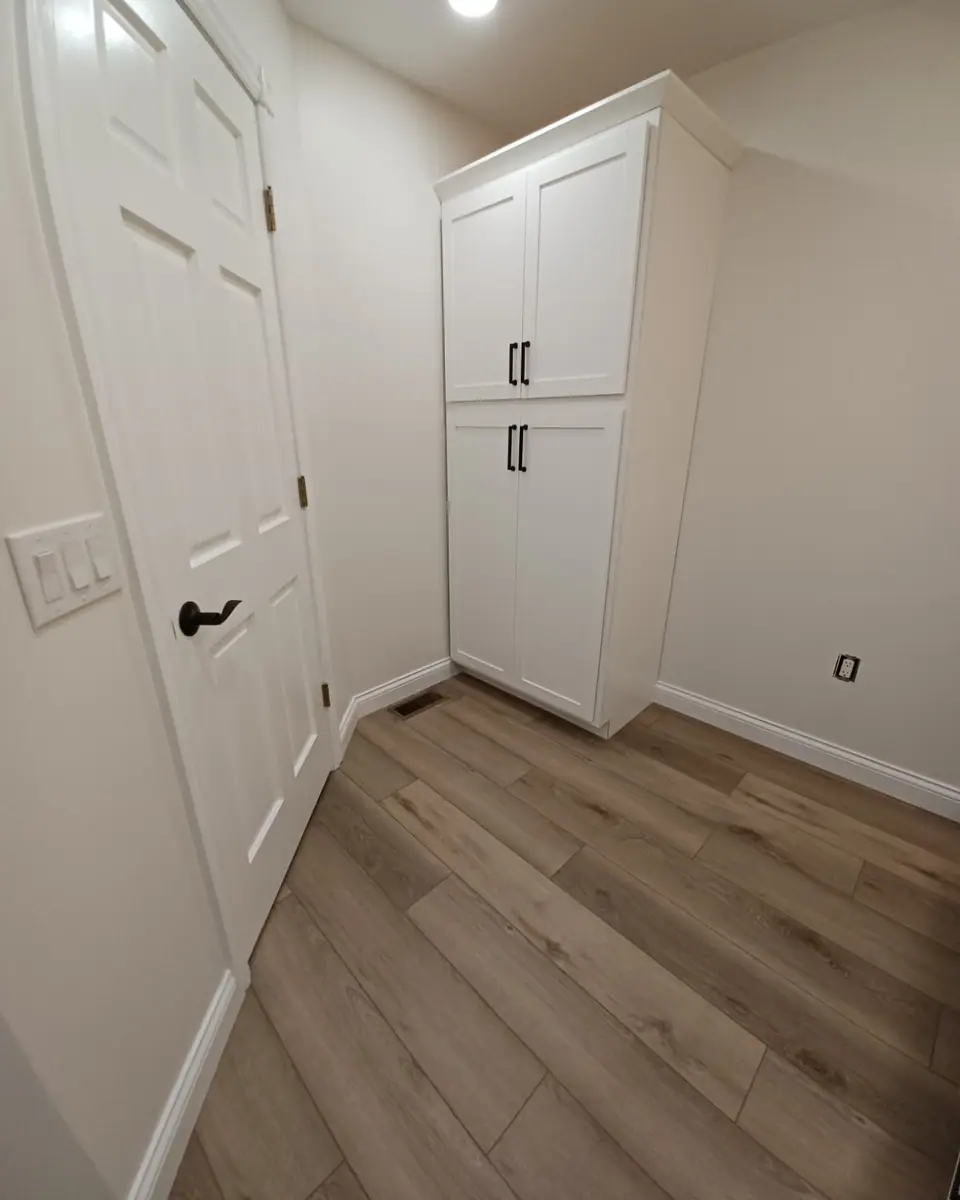 White door with a lever handle, a tall cabinet and baseboard in a finished bathroom, a Dream Big Contracting project