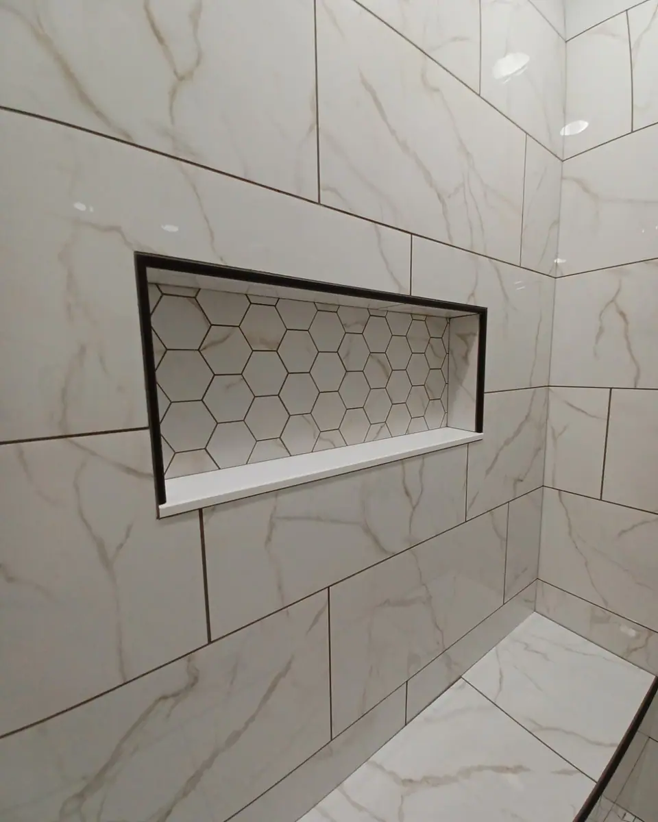 Shower wall of large marble-look tile with a hex-tile niche, a Dream Big Contracting bathroom project